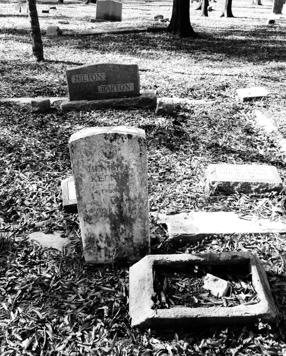 several headstones in a cemetery with trees in the background