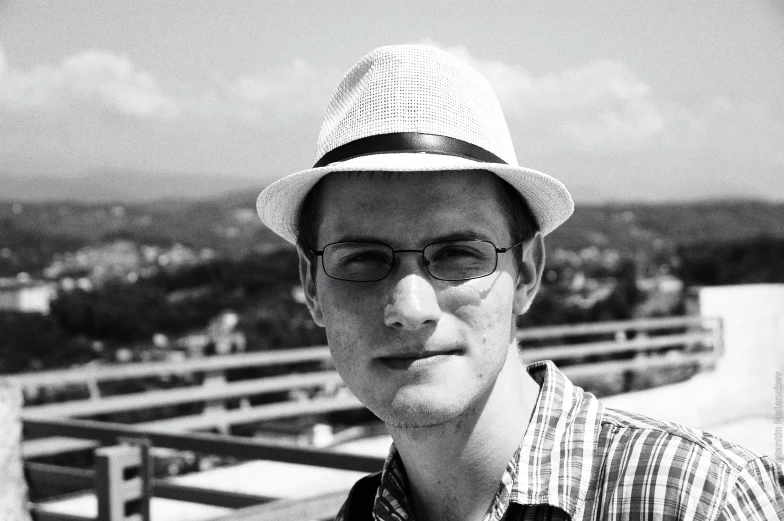 a young man wearing glasses and a straw hat