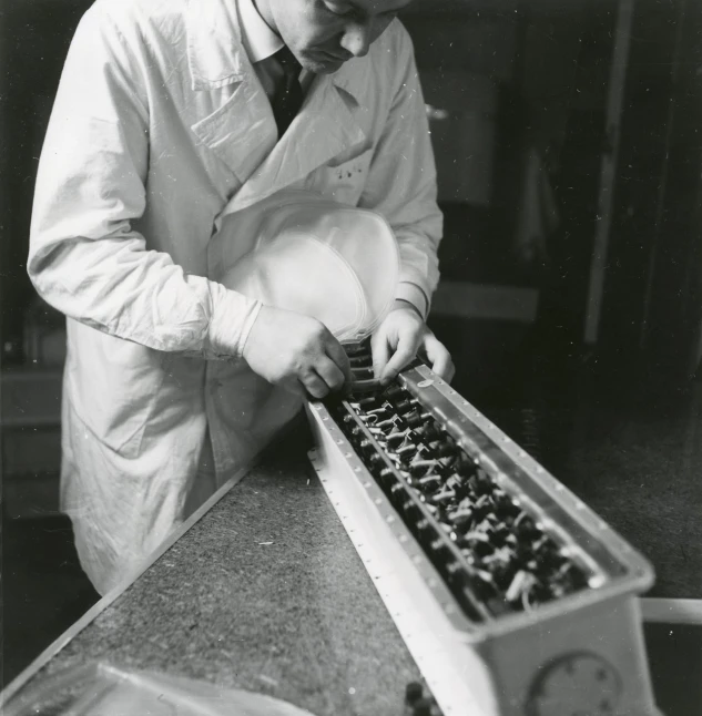 a man wearing a lab coat looking into a drawer