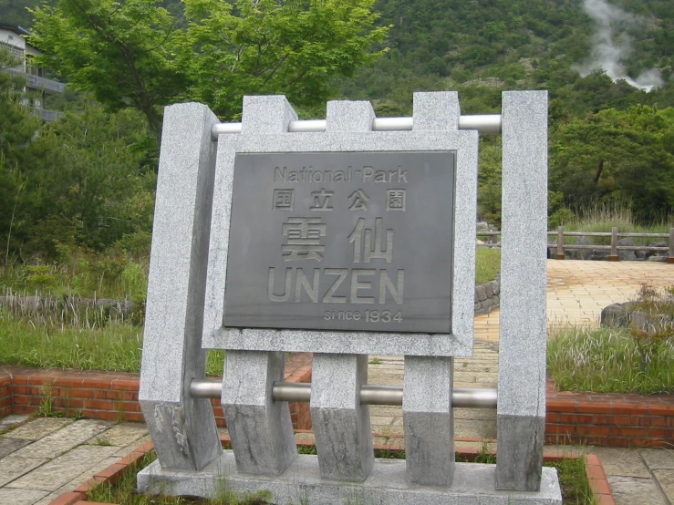 there is a stone park sign in the middle of the forest