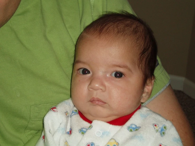 an infant is wearing a bib with a red collar on it