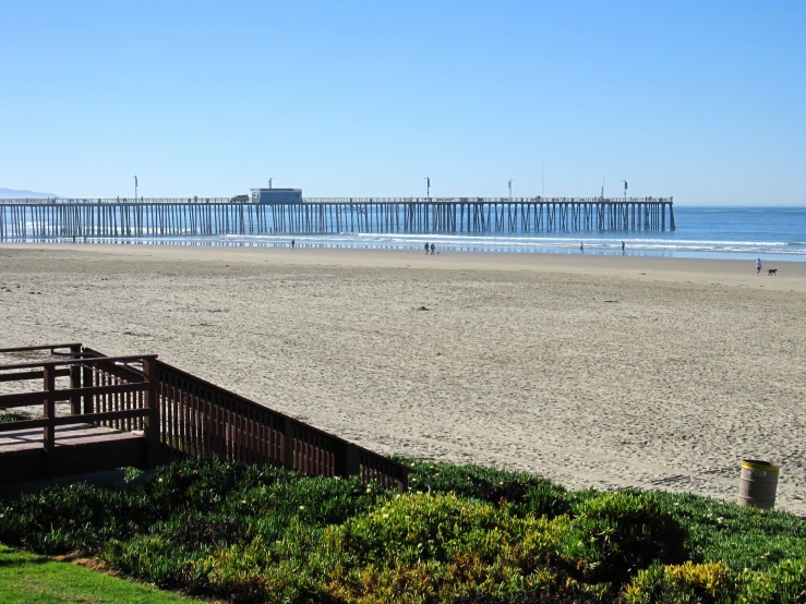 a wooden deck and railing overlook a beach next to the ocean