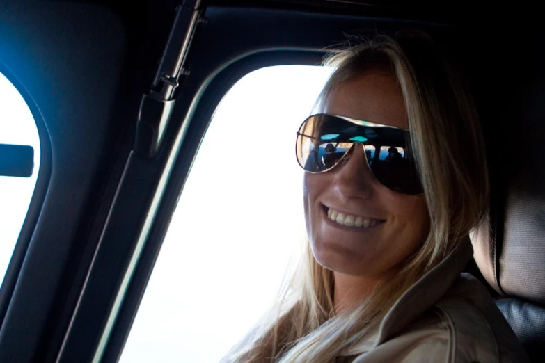 a woman wearing sunglasses sits in a car