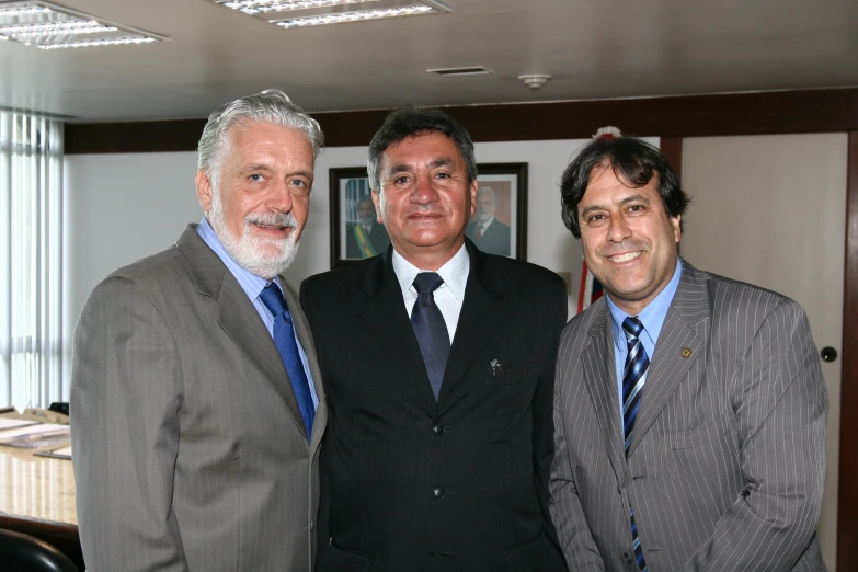 three men pose for the camera in a room