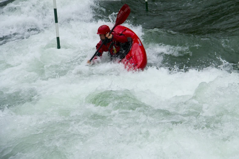 a person wearing a red kayak while in rough water