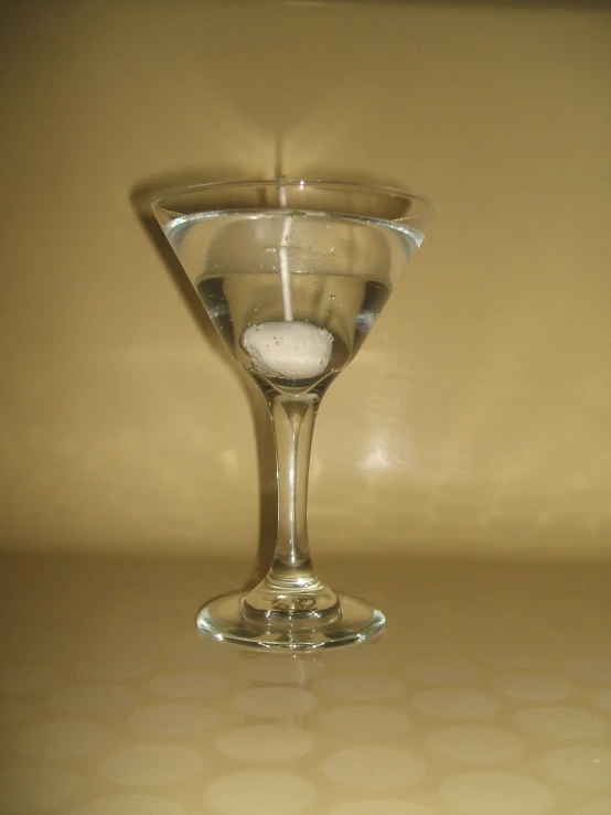 the light from a candle illuminates a martini glass