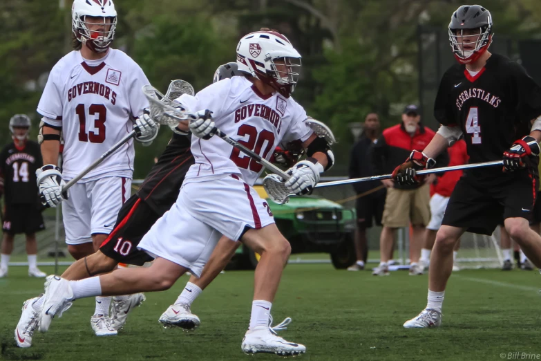 three men in white uniforms playing lacrosse together