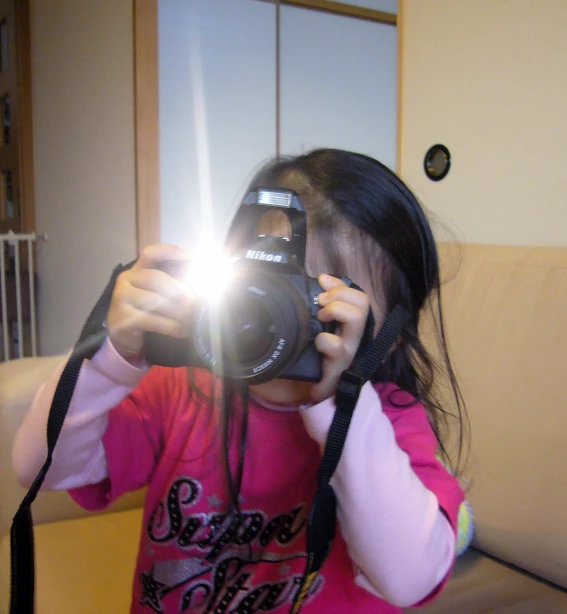 young child taking pograph with camera in living room