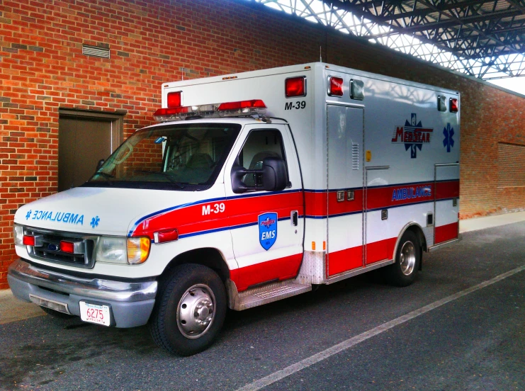 the ambulance is sitting beside the brick building