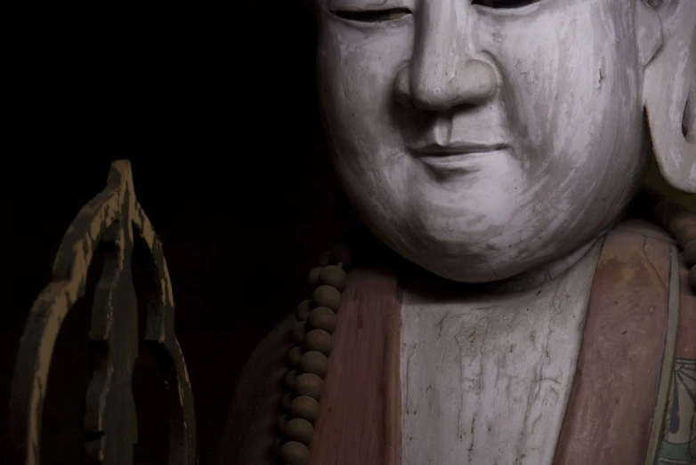 an antique statue of a smiling buddha is displayed