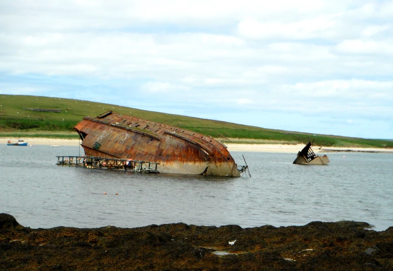 an old boat sitting in some water next to a shore