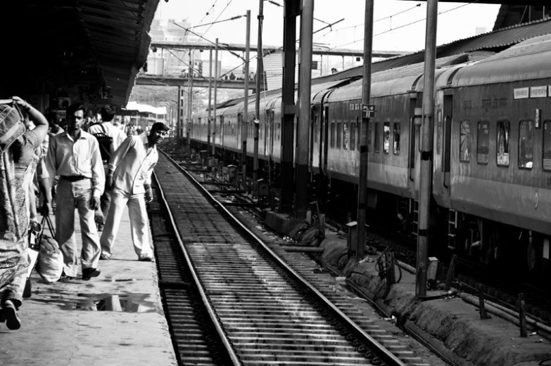 three people walking near a train on a platform