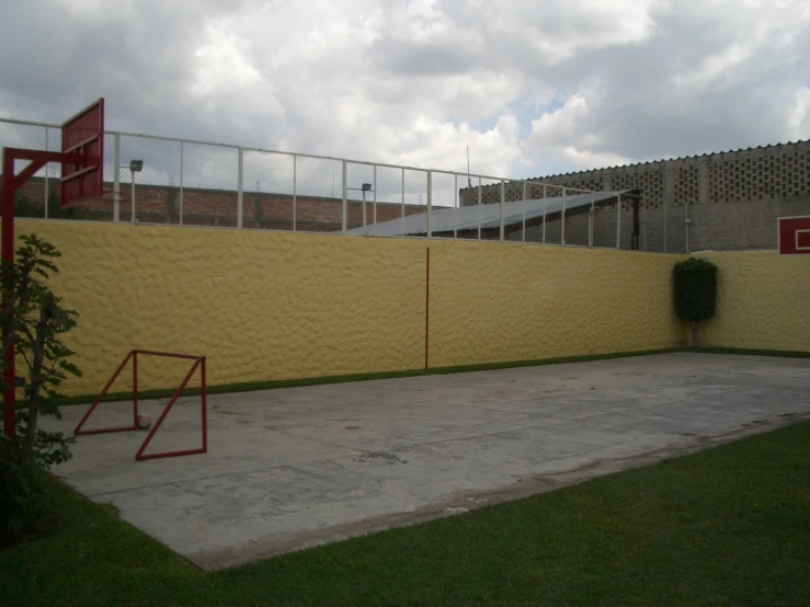 a yellow wall outside a baseball field is next to a small fence