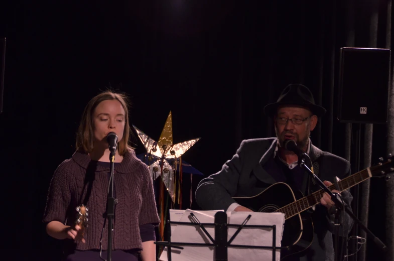 a woman and man singing with guitar, and a microphone