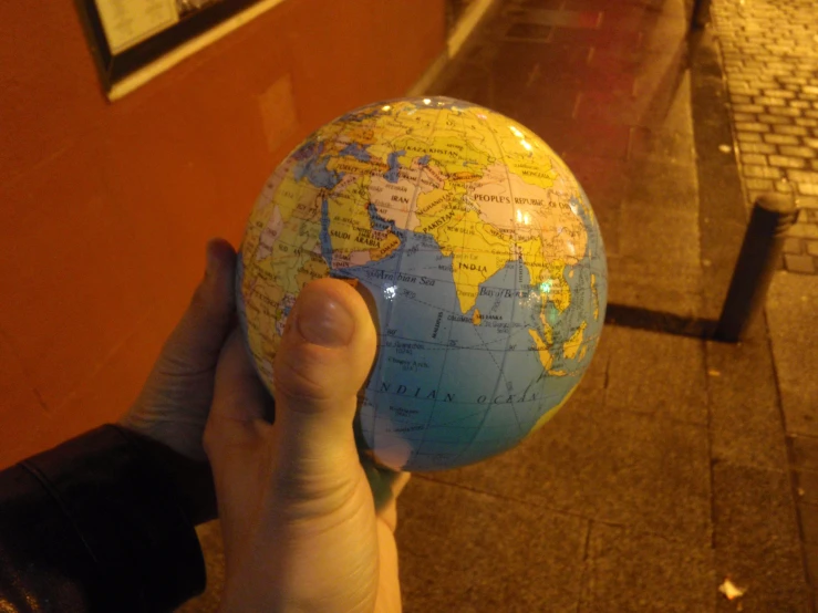 the hand holding a small blue globe has white lines