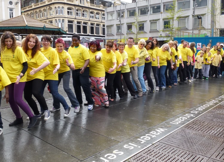 some people in yellow shirts are dancing on a rainy street
