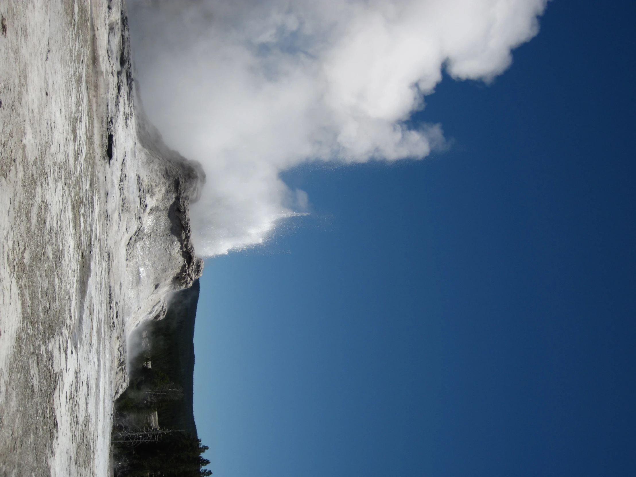 steam rises from a large geyser in the foreground