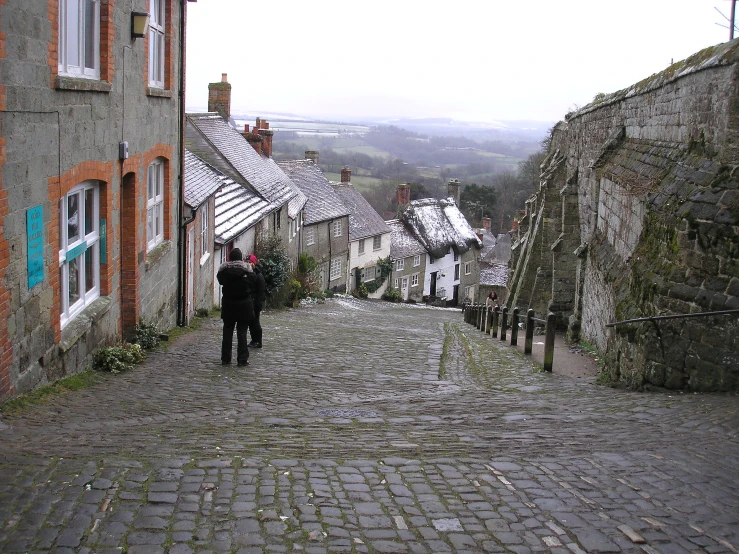 two people walking in an alley between two stone buildings