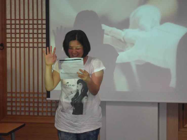 woman giving a presentation with a projection screen and two chairs behind her