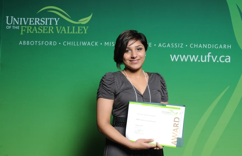 a woman is holding a award with a green and white backdrop