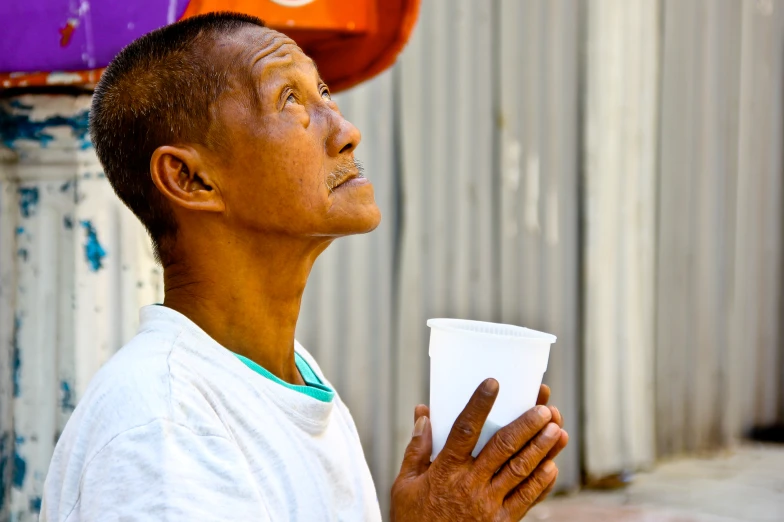 an older man holding up a white cup