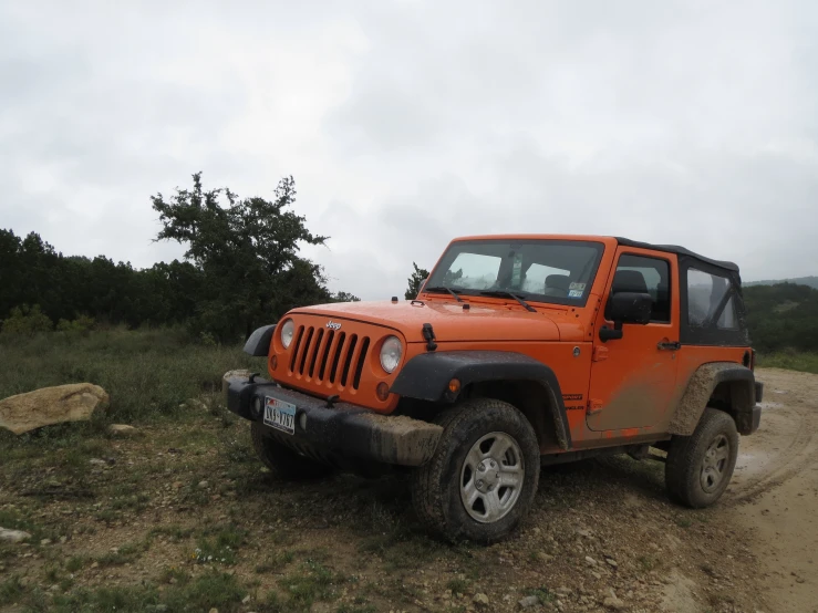 a bright orange jeep driving on a dirt road