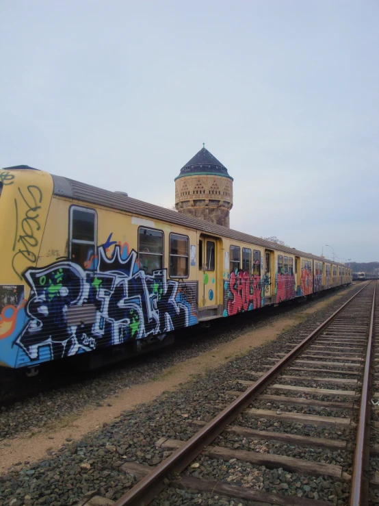 a train covered in graffiti passing a building