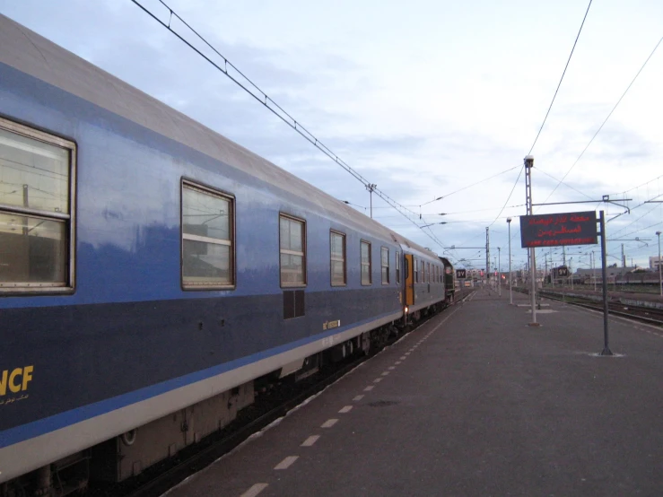 the train is pulling into the station next to the street sign