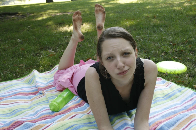 a  laying on her belly and holding her hands up while a frisbee is in the background