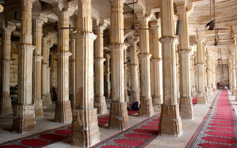 a long row of pillars and rugs on the floor