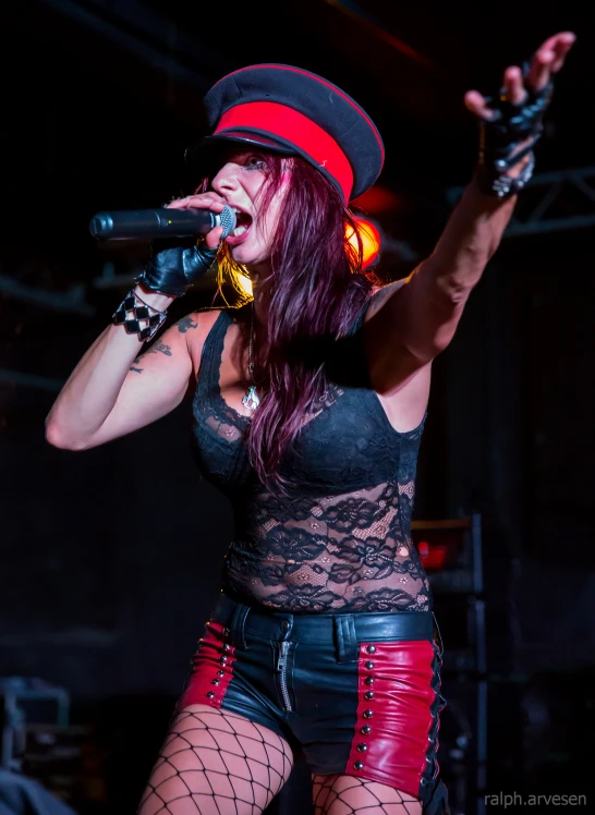 a woman in tights and boots sings into a microphone