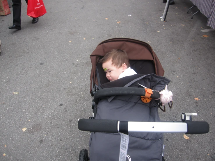 young child lying in stroller and pulling soing behind him