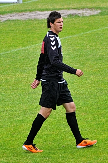 a soccer player walking across the field on a sunny day