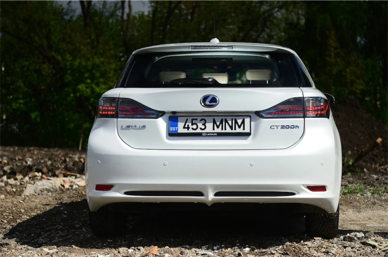 the back of a white car driving on gravel