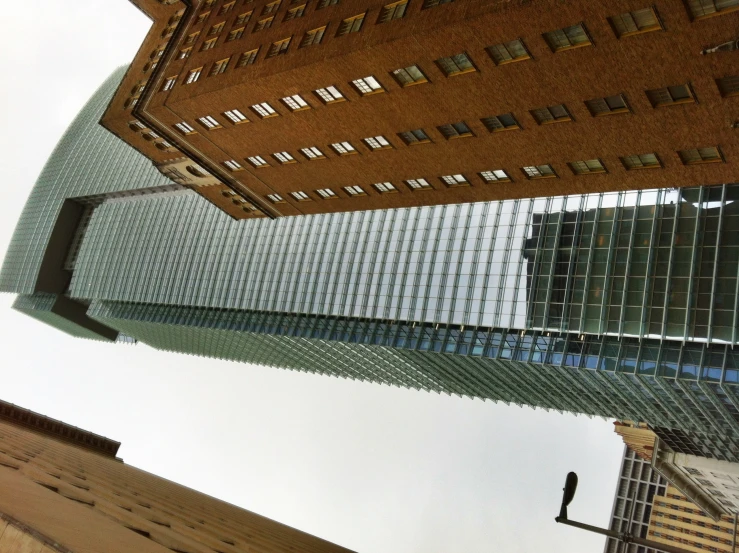 a glass building surrounded by buildings with one high up in the middle