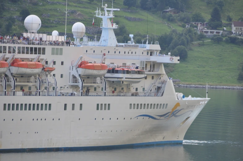 a large boat in the water by a hillside