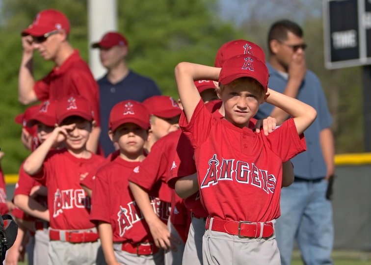 a young baseball player is holding his team's caps