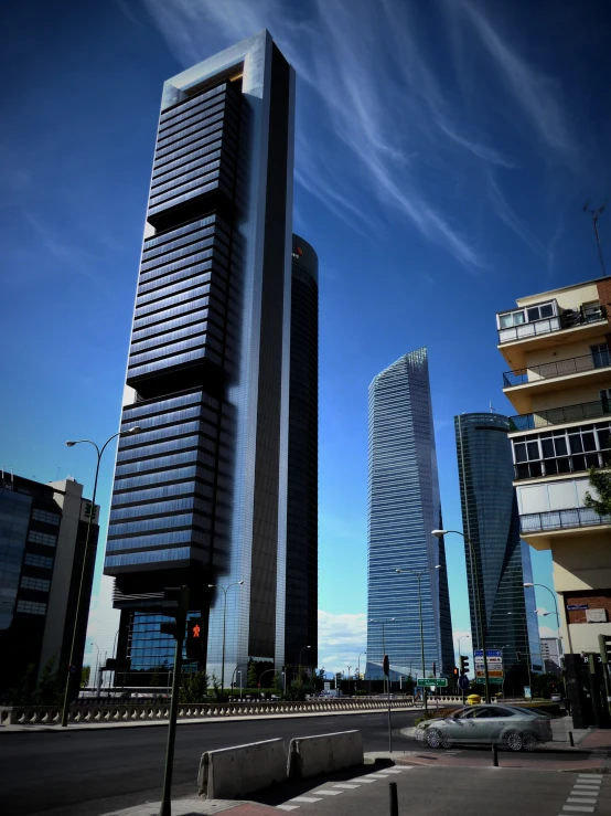 some tall buildings are on the street under blue skies