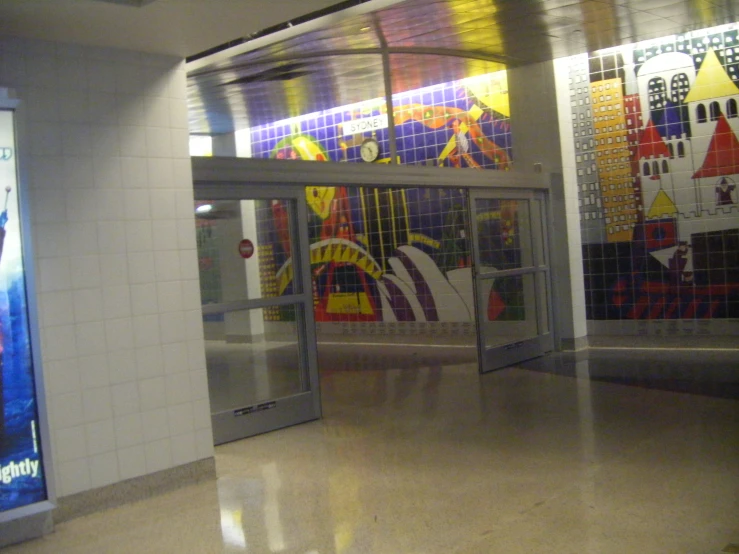 a subway station with art work on the wall and a large glass door