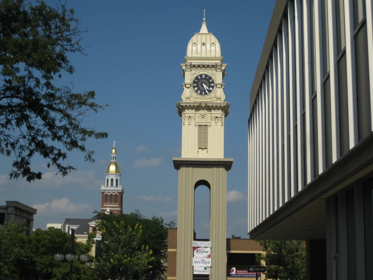 a clock tower standing between buildings in front of a sign