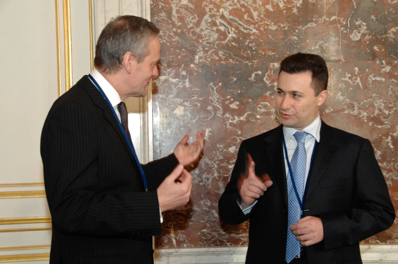 two men standing next to each other while speaking