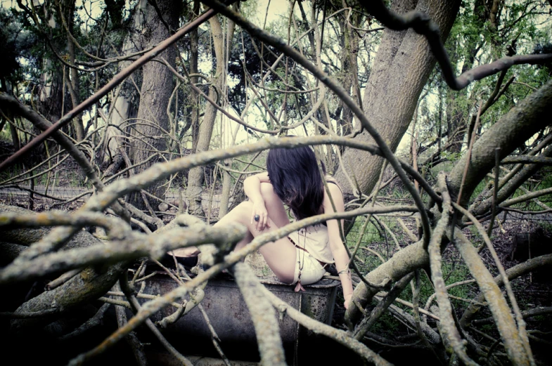 a woman sitting in the middle of a forest