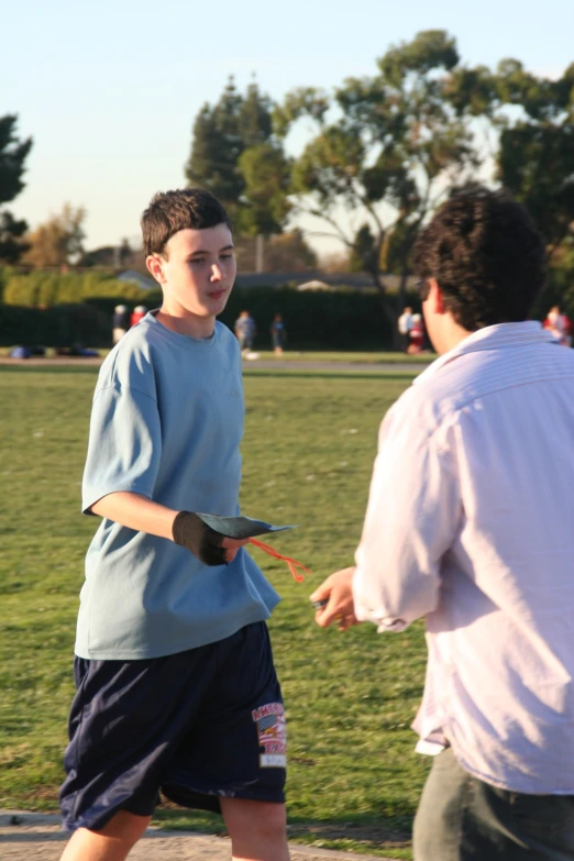 man with a bird on his arm near a man in blue shirt