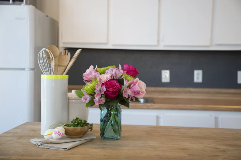 flowers and utensils sit in a kitchen