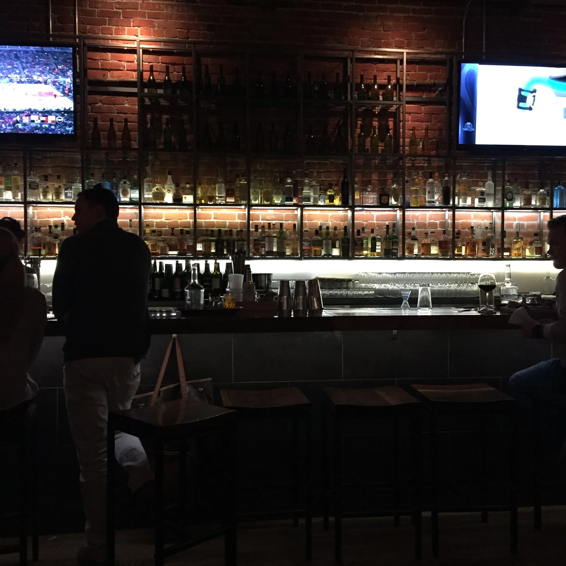 two men standing in front of a bar watching tv