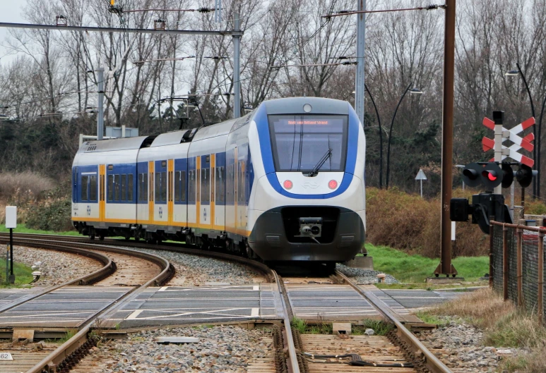 a blue and white train traveling down the tracks