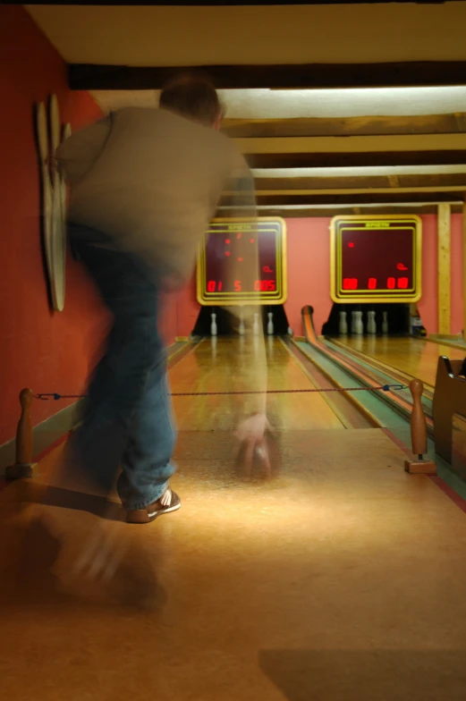 a man in a bowling alley with two bowling pins in the background