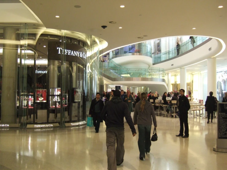 people walking in a lobby under a very high ceiling