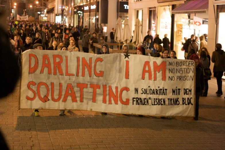 people walking down the street carrying a large sign