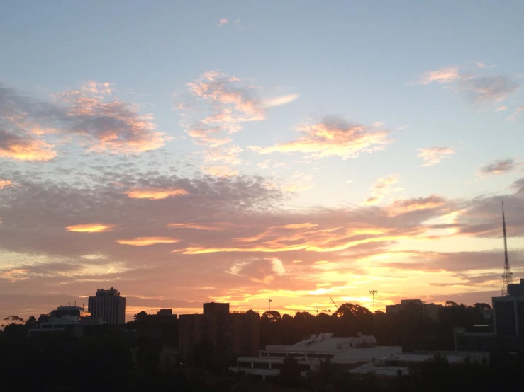 a sunset with a silhouette of buildings in the distance